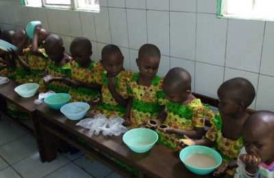 Des enfants sont alignés autour d'une table avec un bol devant eux.